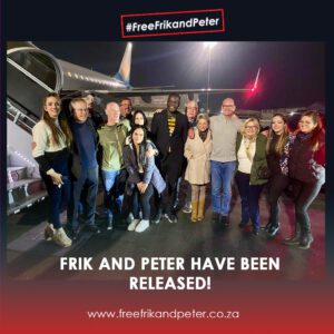 Frik and Peter are released and arrive back in South Africa, celebrating with family and friends at night in front of a plane. Group photo of the recently released Frik and Peter with their family and supporters after returning home.